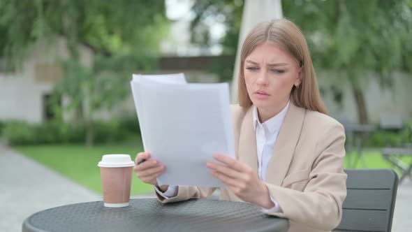 Young Businesswoman Reading Documents in Outdoor Cafe