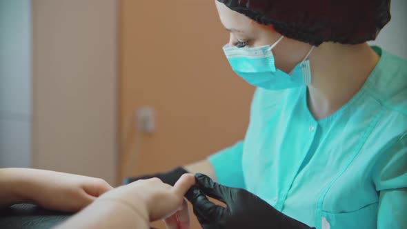 The manicurist carefully processes the nails and prepares them for painting.