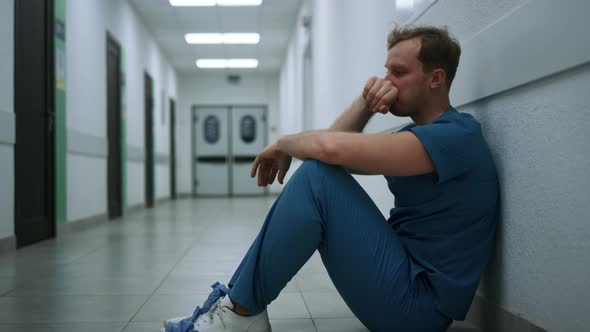 Depressed Doctor Experiencing Hard Emotions Sitting on Clinic Hallway Close Up