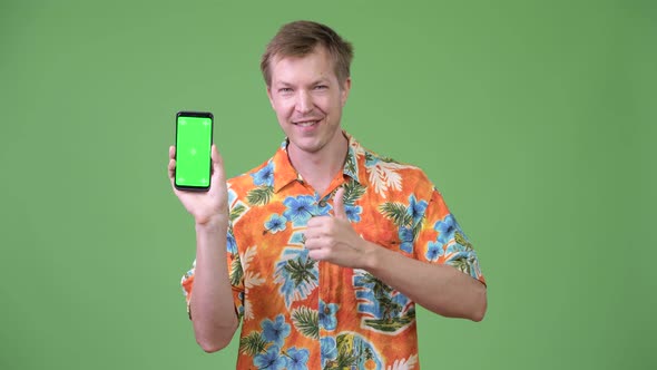 Young Handsome Tourist Man Showing Phone and Giving Thumbs Up