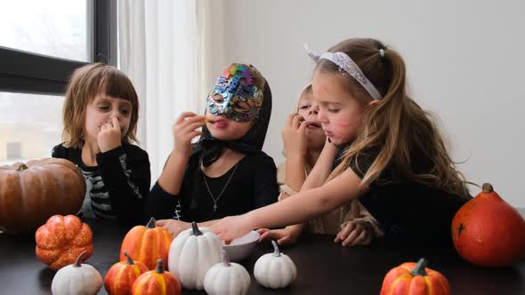 Little Children in Halloween Costumes Eat Treats at Table