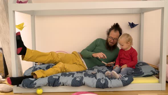 Father reading book to Infant son at children room.
