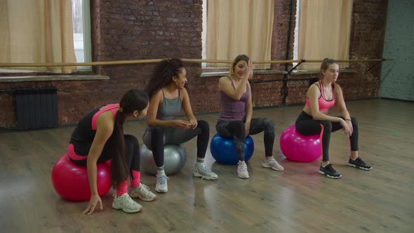 Positive Sporty Fit Women Resting on Fitballs at Gym