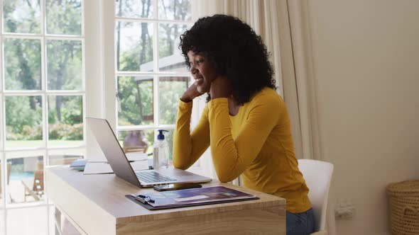 African american woman having a video chat on laptop while sitting on her desk at home