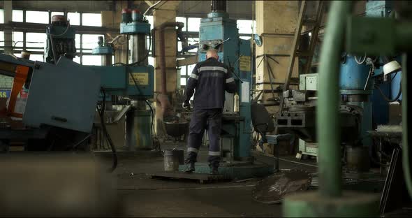 A Professional Worker in Uniform at a Lathe