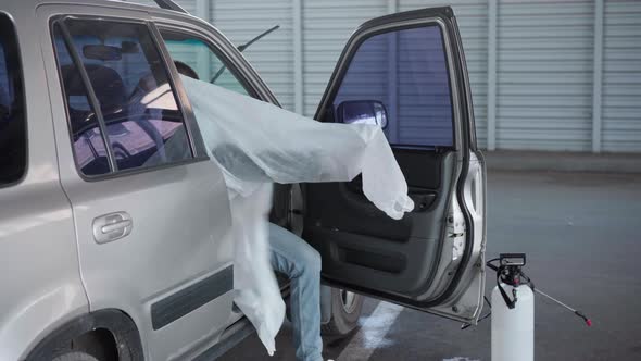 Man Wear Protective White Overall While Sitting in Car on Parking Medical Worker Wear Hazard