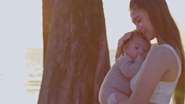 A young Asian mother is on the beach with her baby in summer time