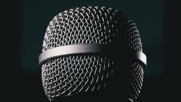 The Microphone Rotates on a Black Background. Dynamic Microphone Grid Spins Close-up alt