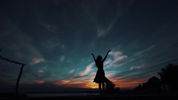 Silhouette of a Ballerina Dancing on Tiptoe Against the Sunset Sky