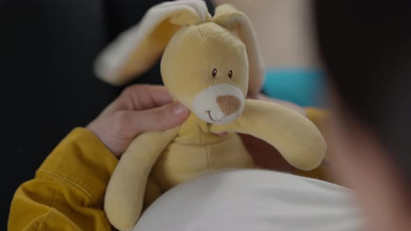 Shooting Over Shoulder of Pregnant Young Woman Playing with Toy Indoors