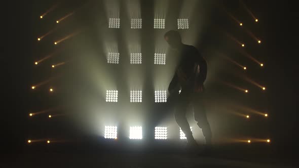 Attractive Guy Dancing Hip-hop in Dark Studio, Neon Light, Lots of Smoke. Silhouette of Cute Man in