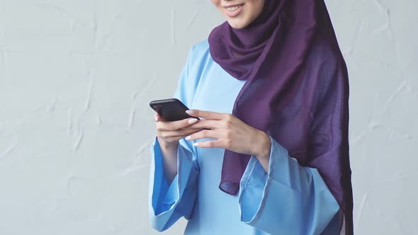 Close-up of Young Muslim Girl Using Smartphone for Online Communication