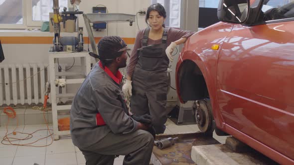 Female Mechanic Speaking with Male Coworker in Auto Repair Shop