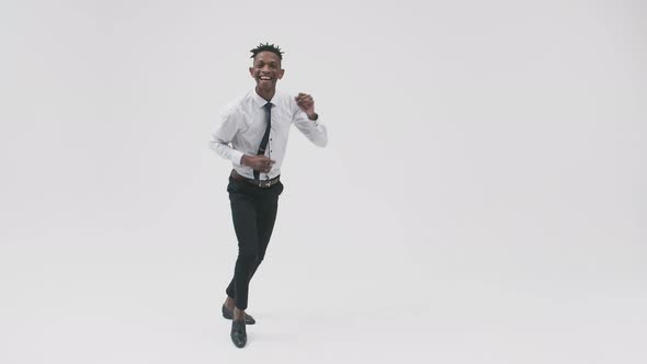 Office Black Man in a Suit Dances Expressively and Smiles Against a White Background