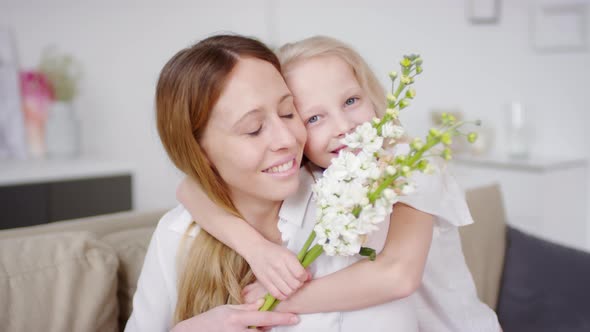 Adorable Girl Holding Flowers and Hugging Mother