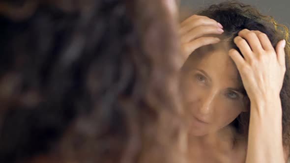 Beautiful Middleaged Woman Examines Her Gorgeous Hair in the Mirror