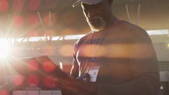 Smiling african american male coach making notes on sunny day