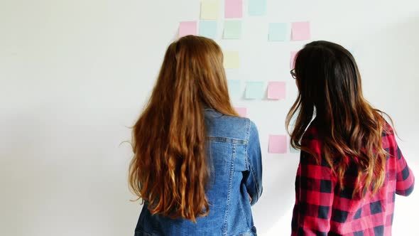 Female executives discussing over sticky notes