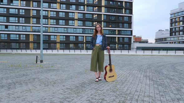 Girl Stands with Classical Guitar in Square