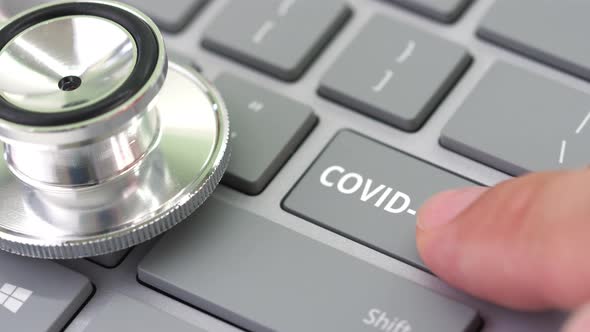 Hand Pushes COVID19 TEST Key on a Keyboard and Stethoscope