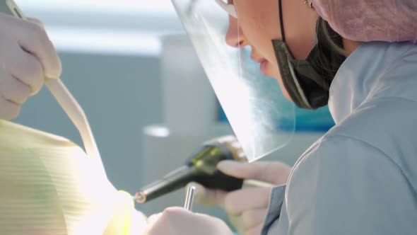 Professional Female Dentist with Assistant Perform an Operation in Dental Clinic