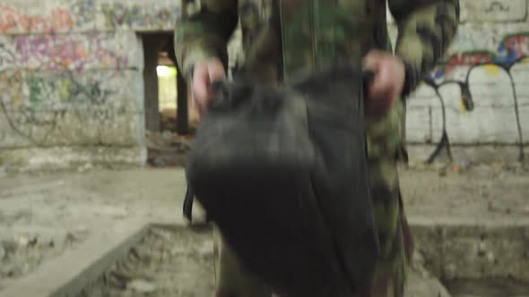 The Sniper Checks the Contents of the Bag and Walks Out of the Building