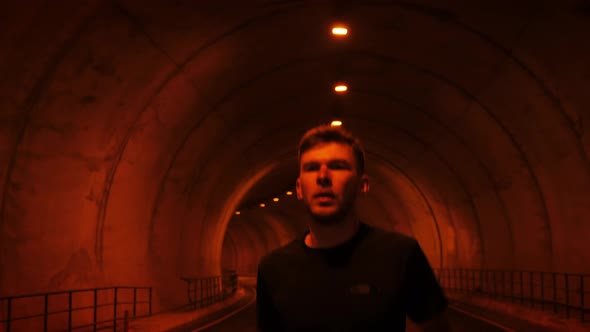 Confident muscular handsome man running along tunnel