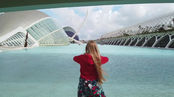 Young Female Looking at the New Modern Future City at a Sunny Day and Raises His Hands To Up.