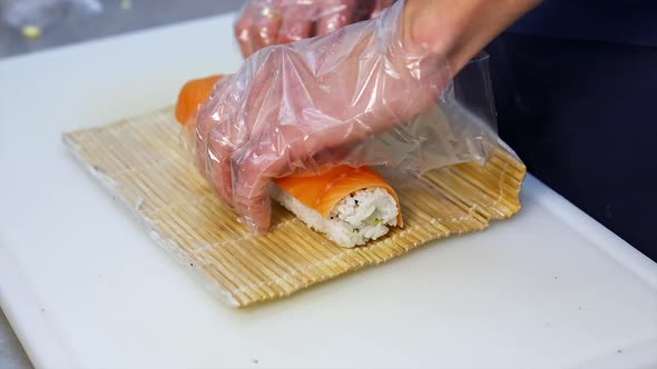 Chef hands preparing japanese food. Close up view of preparation of sushi roll in restaurant