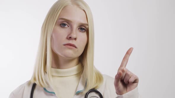 Portrait of Disappointed Young Doctor Showing Thumbs Down