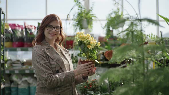 Portrait of Female Florist with Glasses for Vision Choosing Decorative Blooming Plants in Pots for