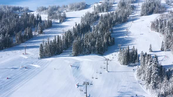 Aerial View of Ski Resort with People Skiing and Snowboarding Down the Hill