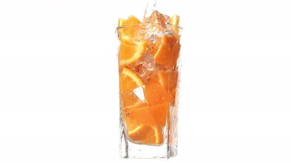 Pouring Stream Mineral Water Rotation Glass with Organic Sweet Orange Pieces Slow Motion Isolated