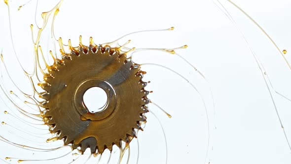 Super Slow Motion Shot of Rotating and Splashing Metal Cogwheel on White Background at 1000 Fps