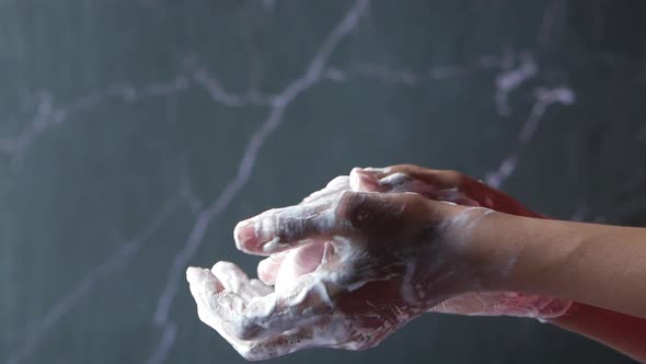 Slow Motion of Man Washing Hands with Soap Against Black Background