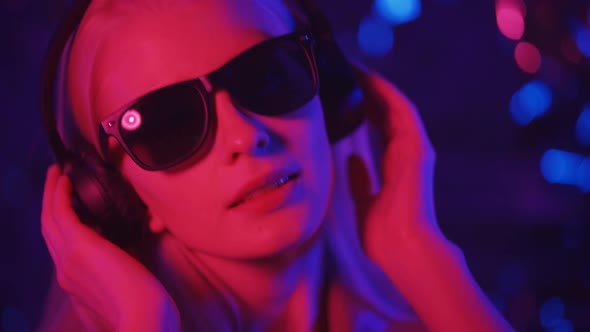 Stylish Young Blonde Woman Vigorously Dancing in Headphones and Sunglasses