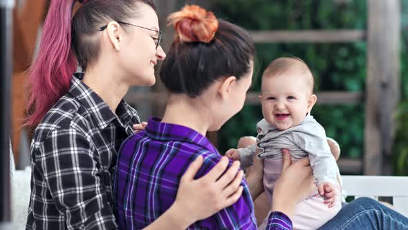 Medium Closeup Happy Laughing Cute Toddler Enjoying Playing with Same Sex Parents at Home