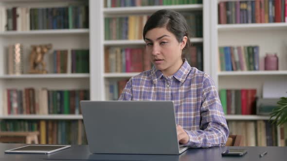 Indian Woman Showing Thumbs Down Sign While using Laptop in Office