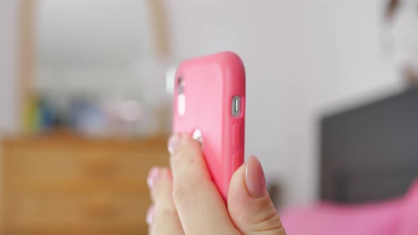 Woman Holding a Pink Phone Looking at Social Networks on It