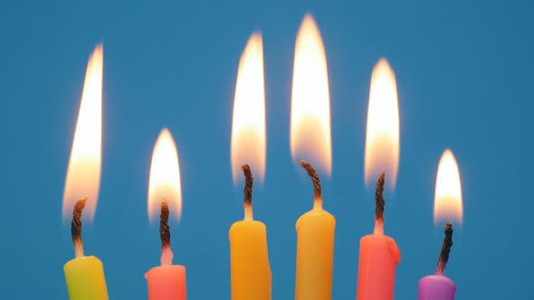 Lighted Candles in a Birthday Cake on a Blue Background