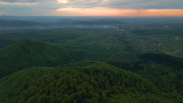 Aerial view of dark mountain hills covered with green mixed pine and lush forest in evening. alt