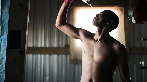 Boxer pouring water on his face in the gym