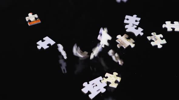 Slow motion of randomly falling pieces of the puzzle filling the black background