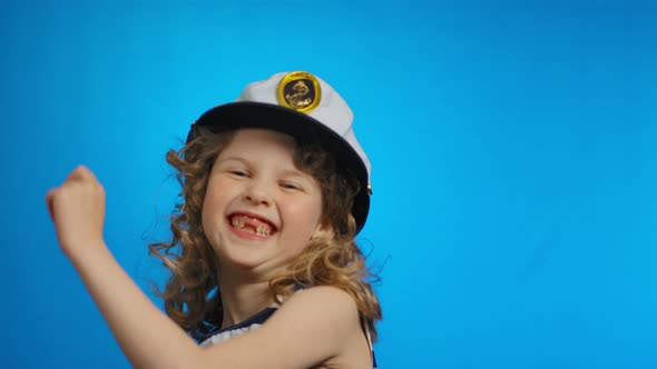 A Little Curly Sailor Girl is Dancing and Smiling Cheerfully in the Studio