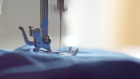 Close-up of a Sewing Machine Needle Stitching Blue Fabric. The Sewing Machine Stitches the Blue