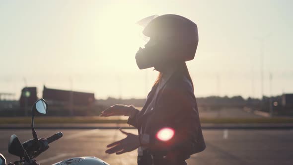 Beautiful Young Redhaired Woman Motorcyclist Dancing on Her Custom Bike in Black Motorcycle Helmet