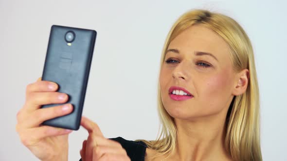 A Young Attractive Woman Takes Selfies with a Smartphone - Closeup - White Screen Studio