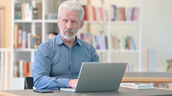 Upset Old Man with Laptop Doing Thumbs Down