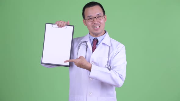 Happy Asian Man Doctor Showing Clipboard and Giving Thumbs Up