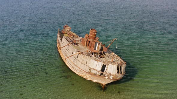 A Wrecked Wooden Ship Lies on the Seashore Covered with Rust